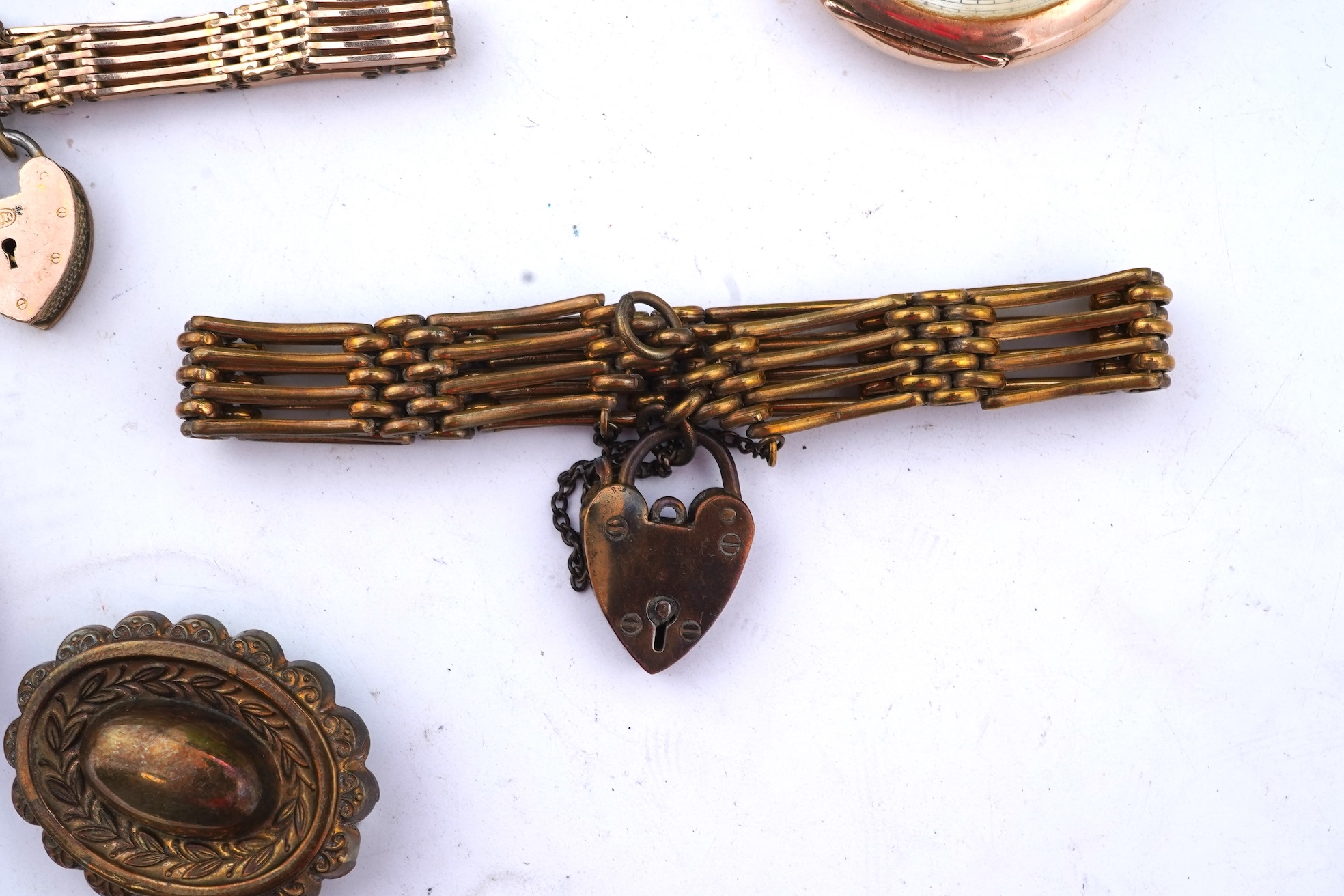 A group of gilt metal/pinchbeck jewels, 19th and early 20th century, comprising: a brooch of knotted design; two gate bracelets; a fancy link bracelet; an open-faced pocket watch; two oval panel brooches, and two watch c